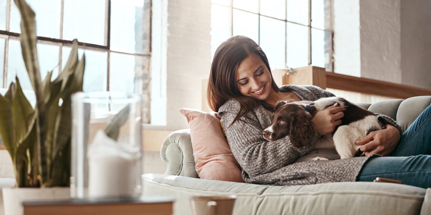 lady and dog resting on couch with great peace of mind - Now’s the Perfect Time to Book Your Furnace Tune-Up. Here’s Why! 