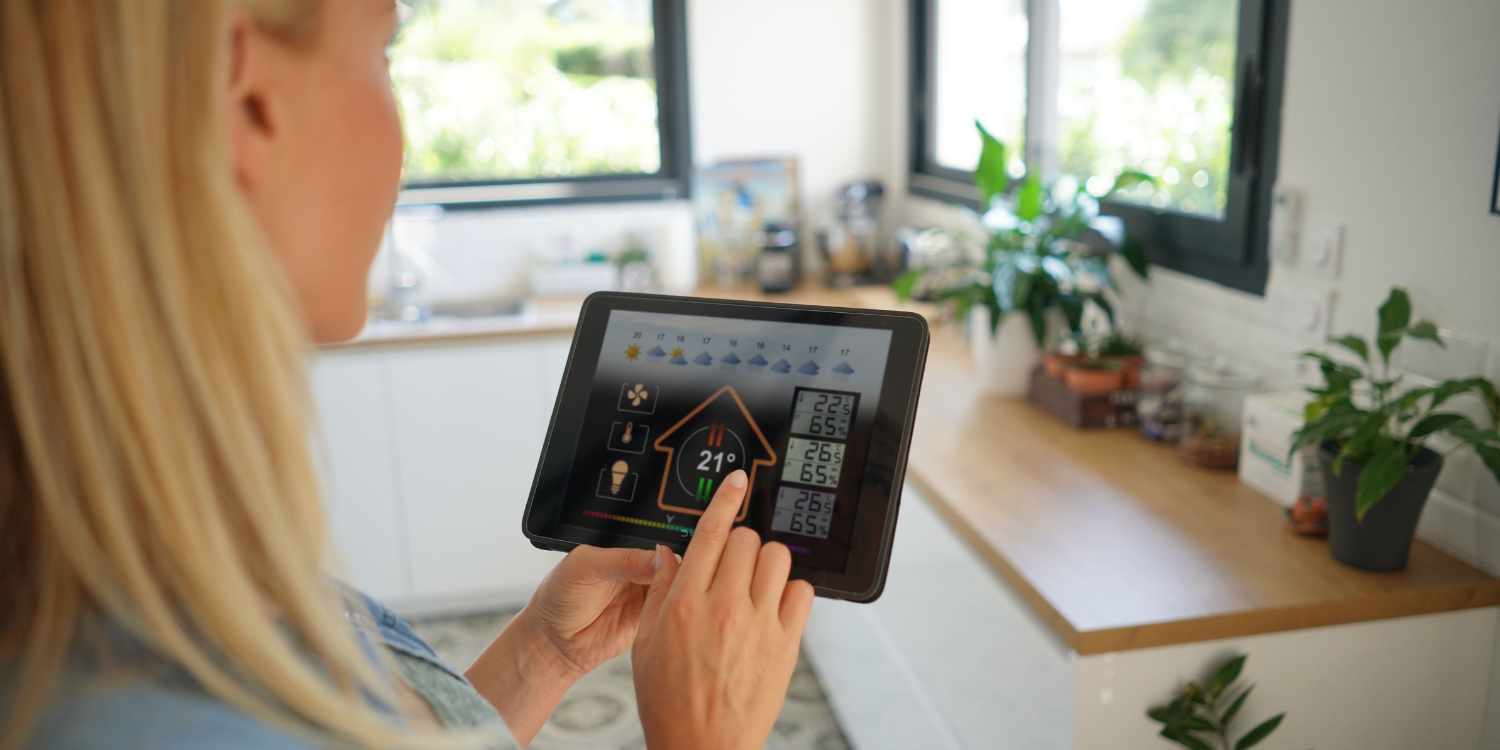 Women changing thermostat settings via tablet - New Year’s Resolutions for Your HVAC System
