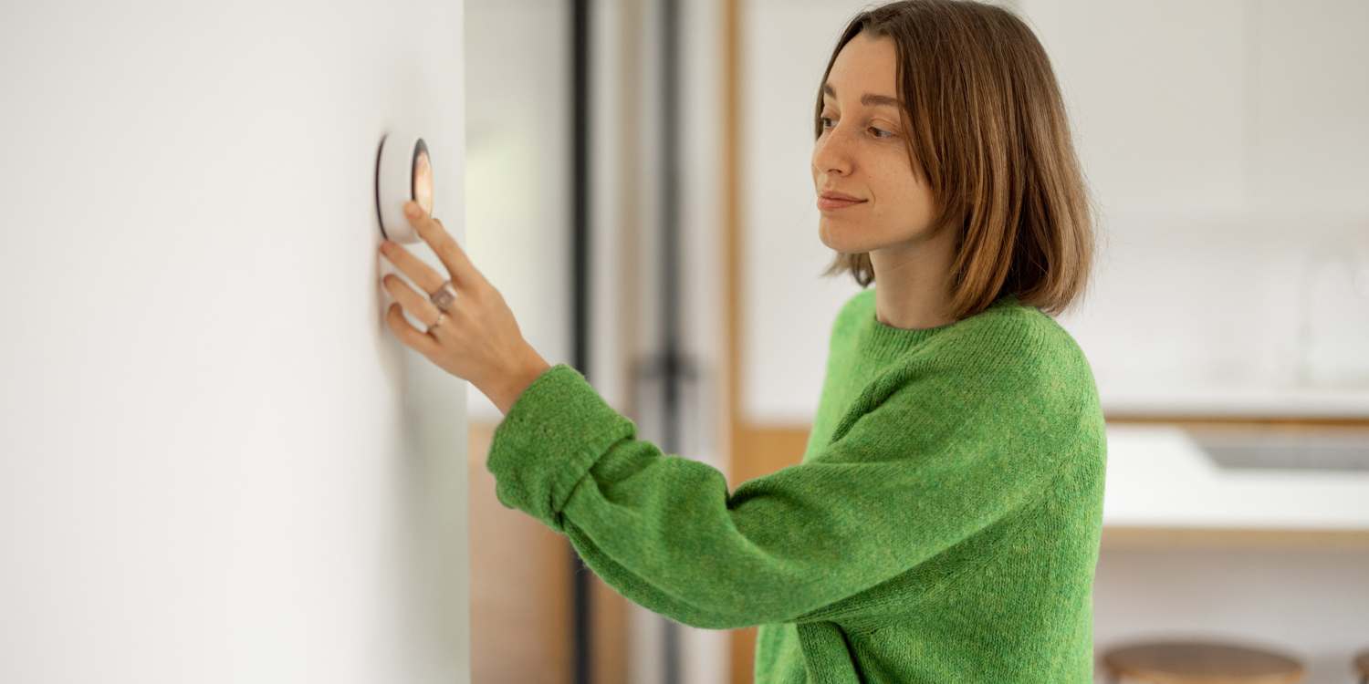 Lady setting a smart thermostat - Winter's Coming: How to Slash Your Heating Bills in 7 Steps 